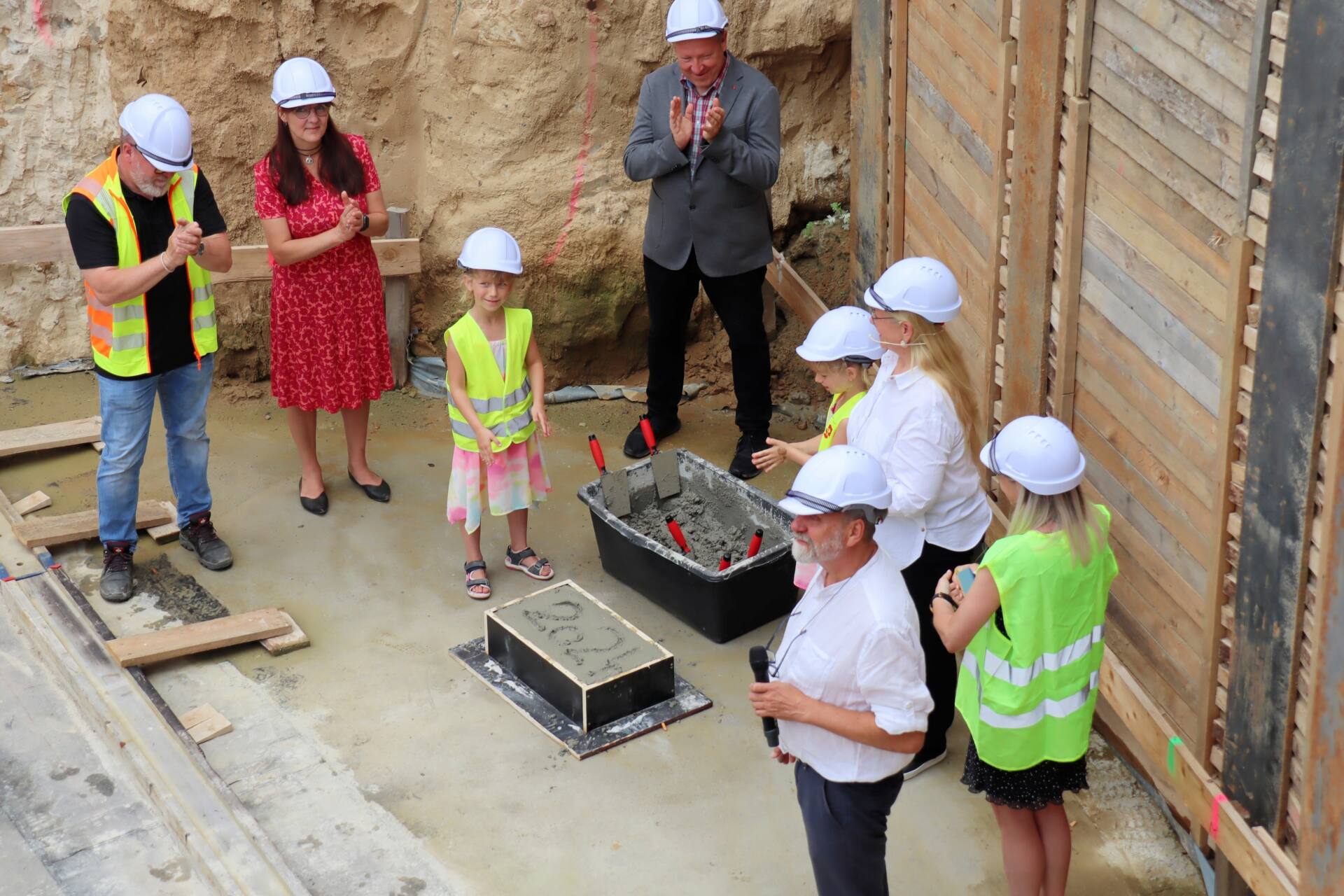 Menschen bei der Grundsteinlegung in einer Baustelle.